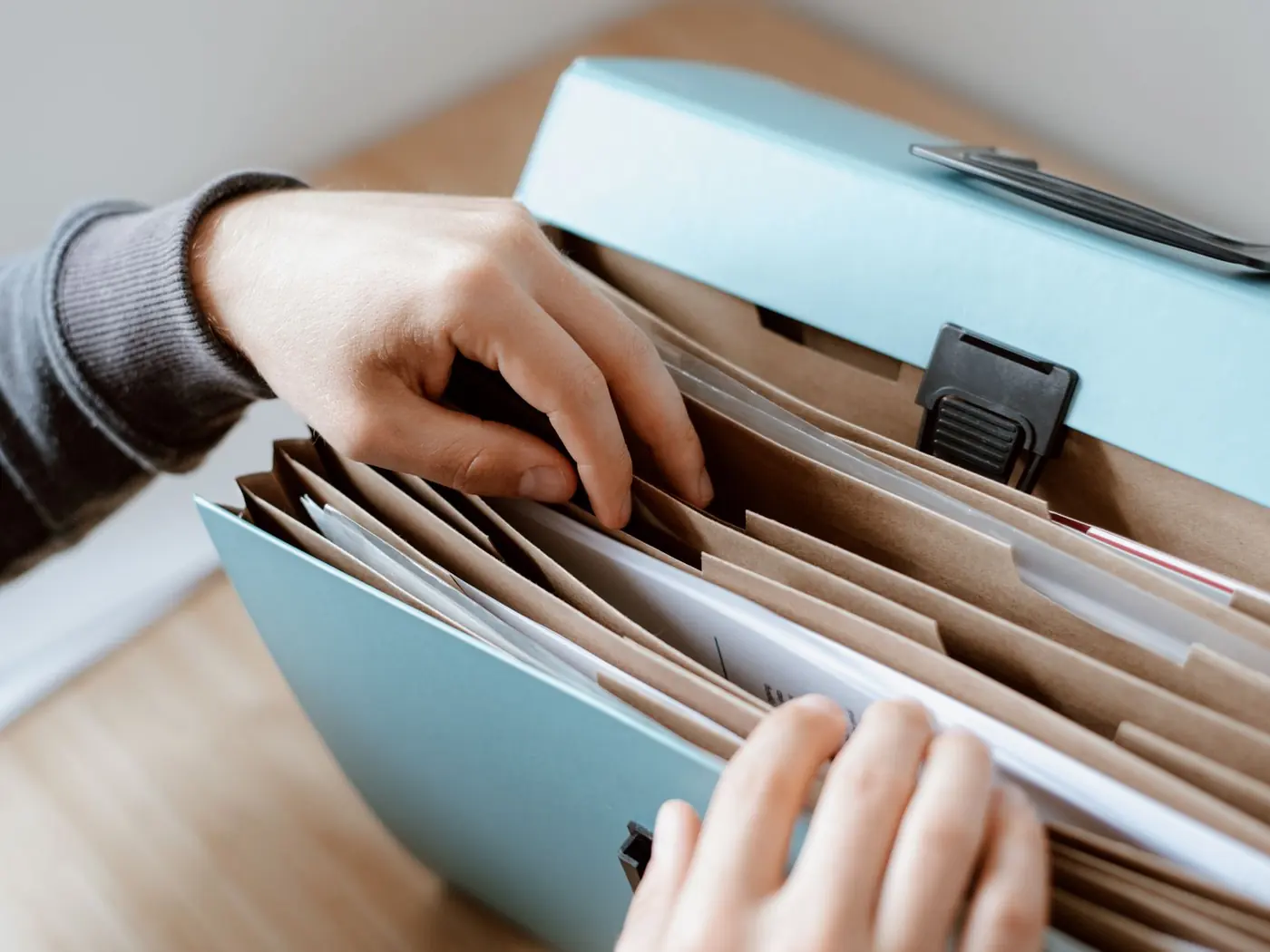 Manos de un asesor sacando un documento de un clasificador de expedientes