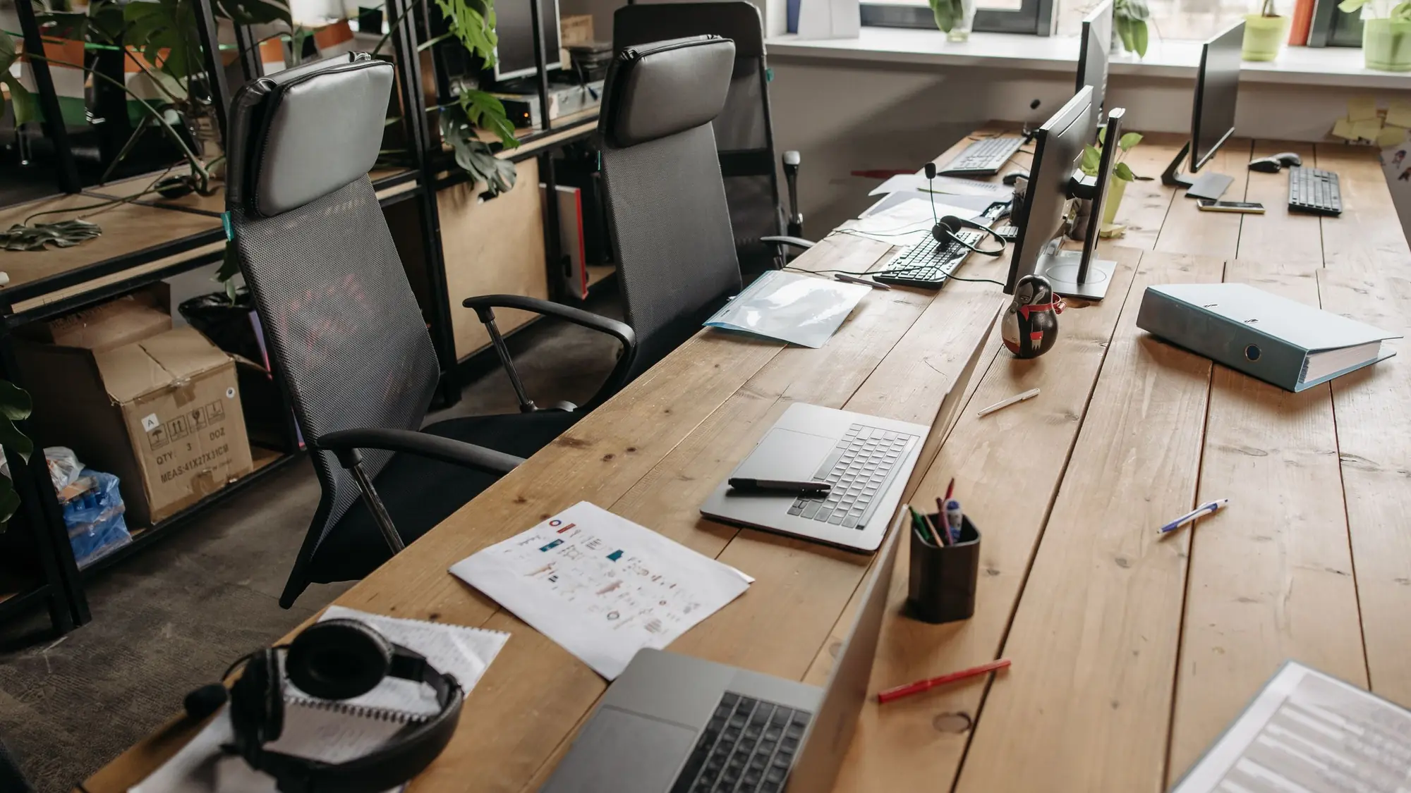 Puestos de trabajo de una asesoría con ordenadores, archivadores y documentación sobre la mesa